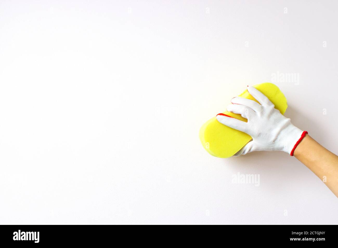 hand holds sponge and washing a wall on a white background. Cleaning or housekeeping concept background Stock Photo