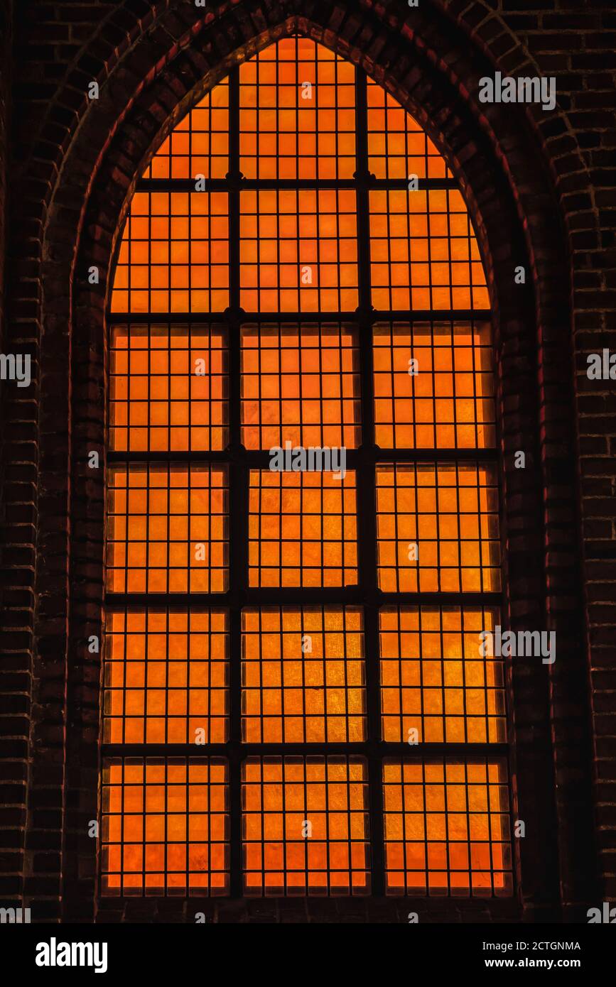 Deep orange light coming from a church 's Gothic window conveys a diabolic, hellish and evil feeling with wicked, cruel and bad concept. Powerful and Stock Photo