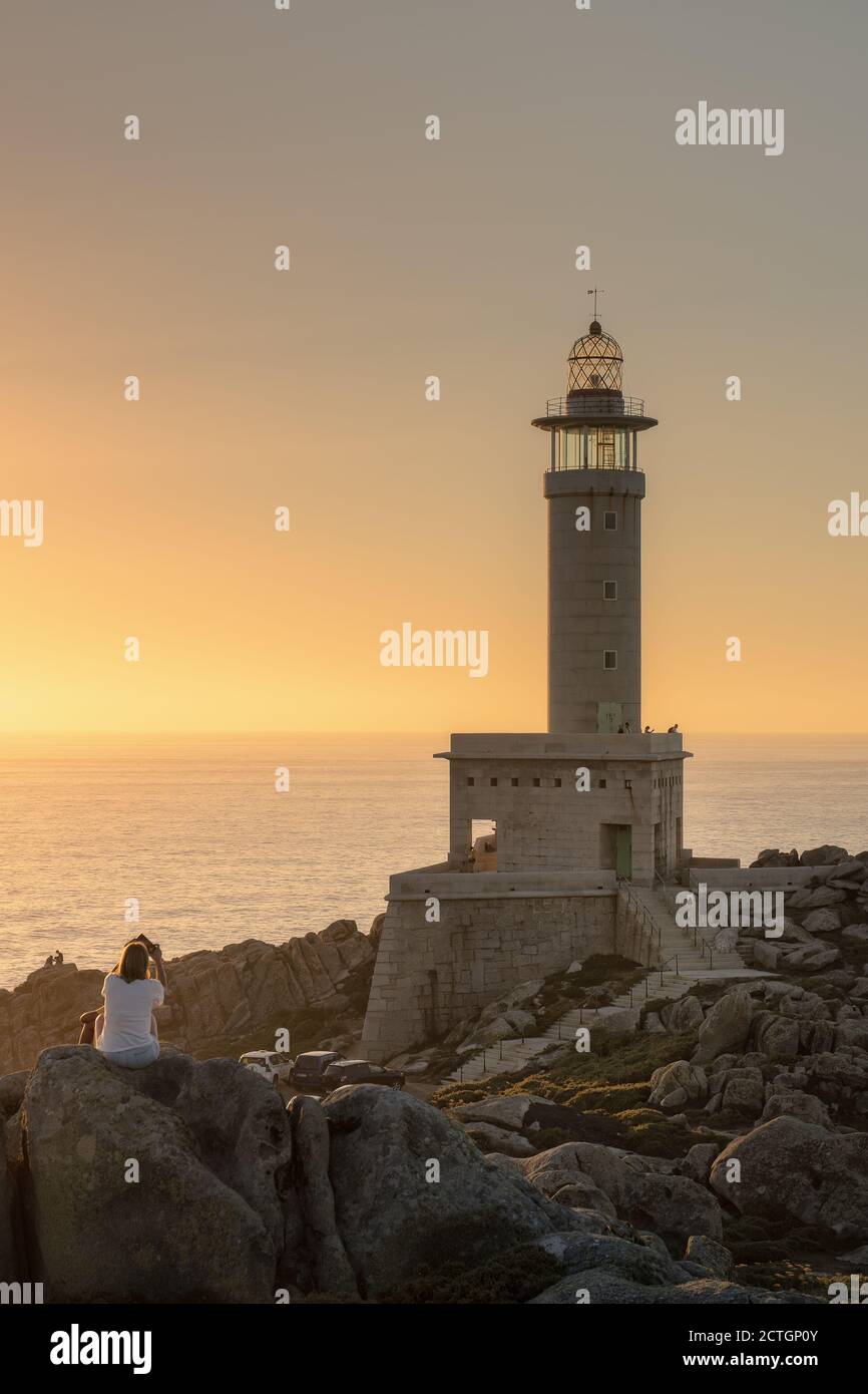 MALPICA DE BERGANTIñOS, SPAIN - Aug 24, 2020: Tourists observe the Punta Nariga lighthouse, the most modern in Galicia, during the sunset. Stock Photo