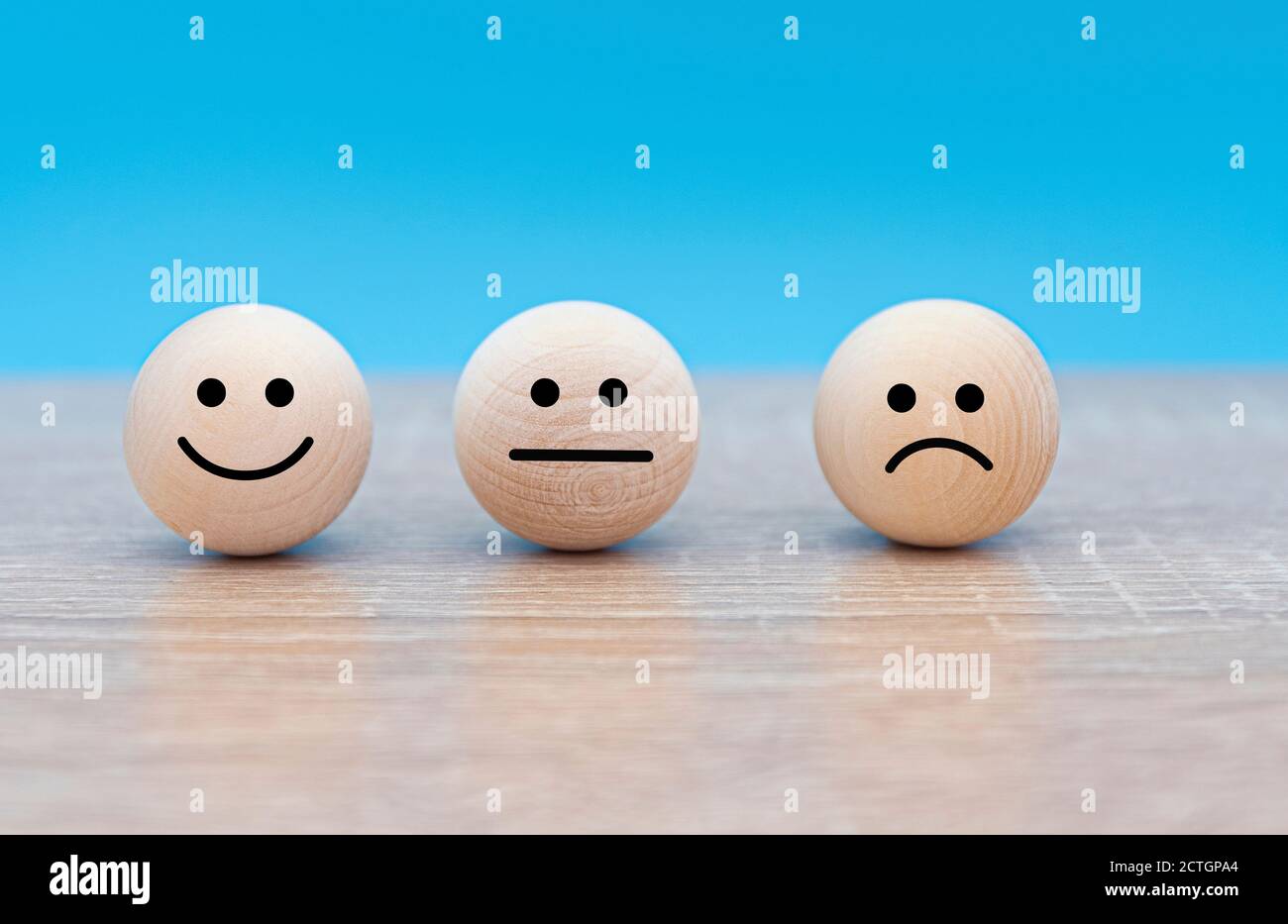 Three wooden faces with emotions: smile - happy, serious - neutral and angry - displeased, concept picture Stock Photo