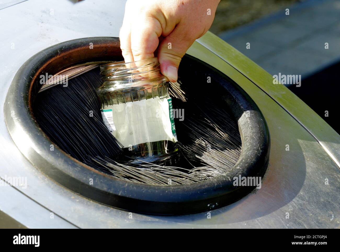 A man dropping empty glass jar into container for separation of home waste. A sign of awareness concerning environment, waste management, and climate. Stock Photo
