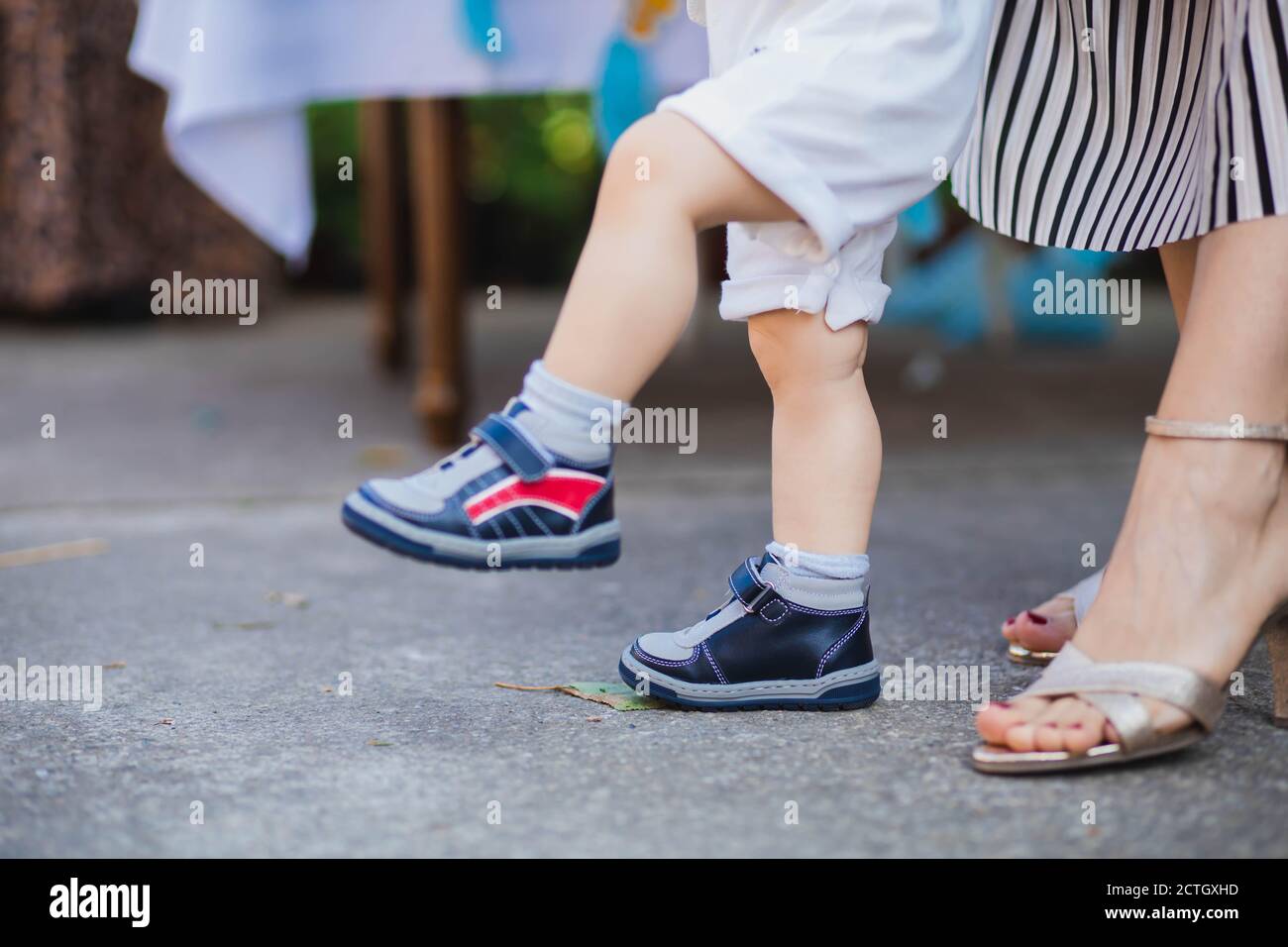 Mom helping her baby son to walk. Parenting concept Stock Photo