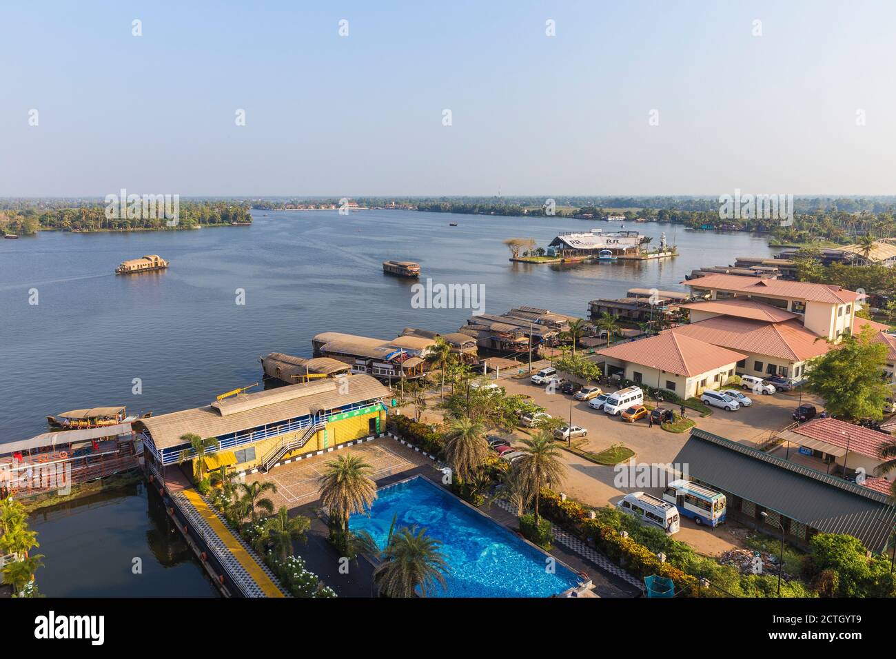 India, Kerala, Alappuzha (Alleppey), View over hotel swimming pool towards houseboats on backwaters Stock Photo