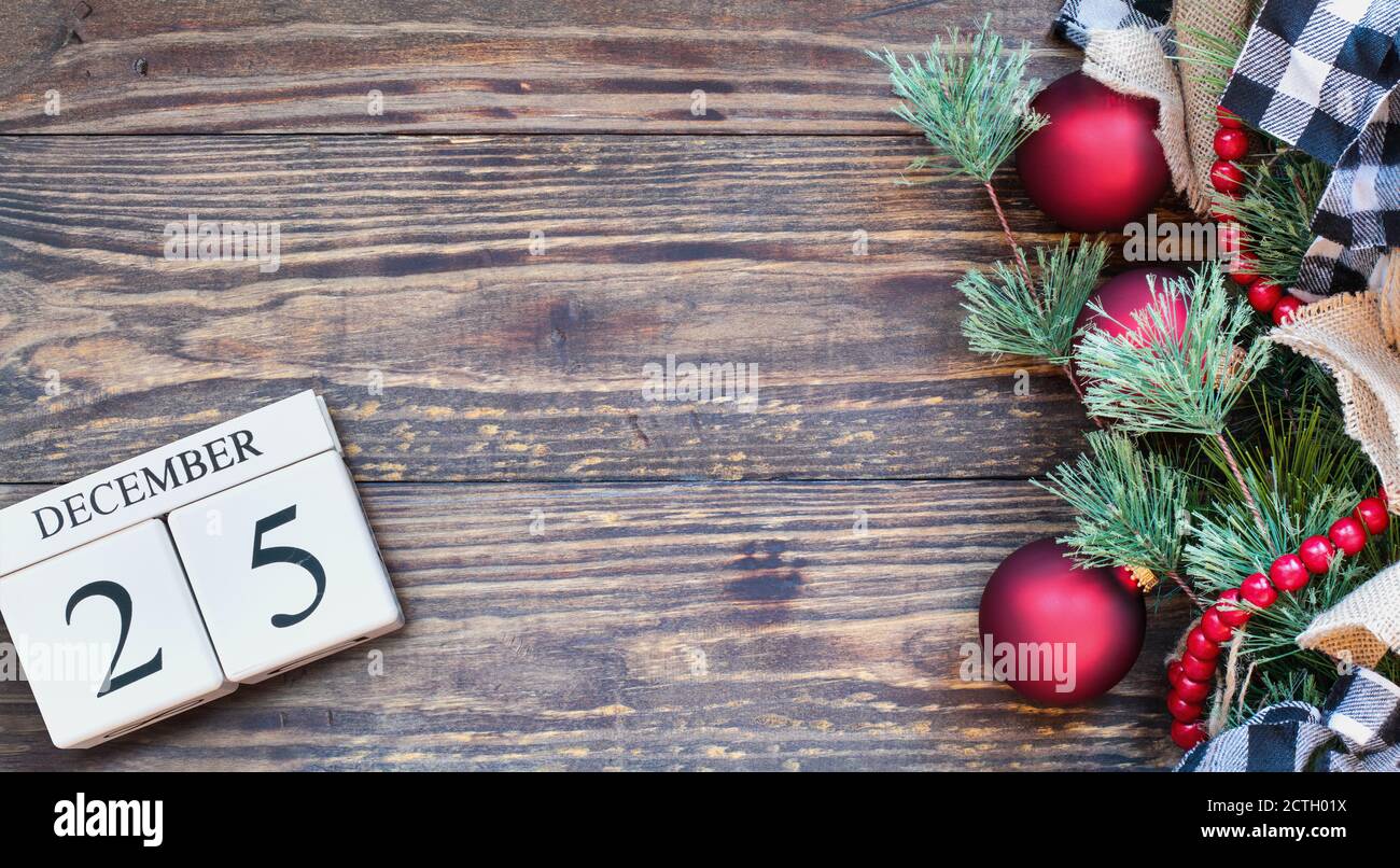 Wood calendar blocks with the date December 25th to mark Christmas Day with holiday trim of ornaments, black and white buffalo check ribbon, burlap an Stock Photo