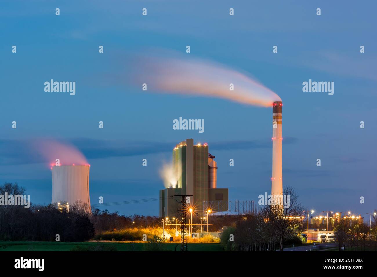 Large industrial plant with cooling tower and smoking chimney at night Stock Photo