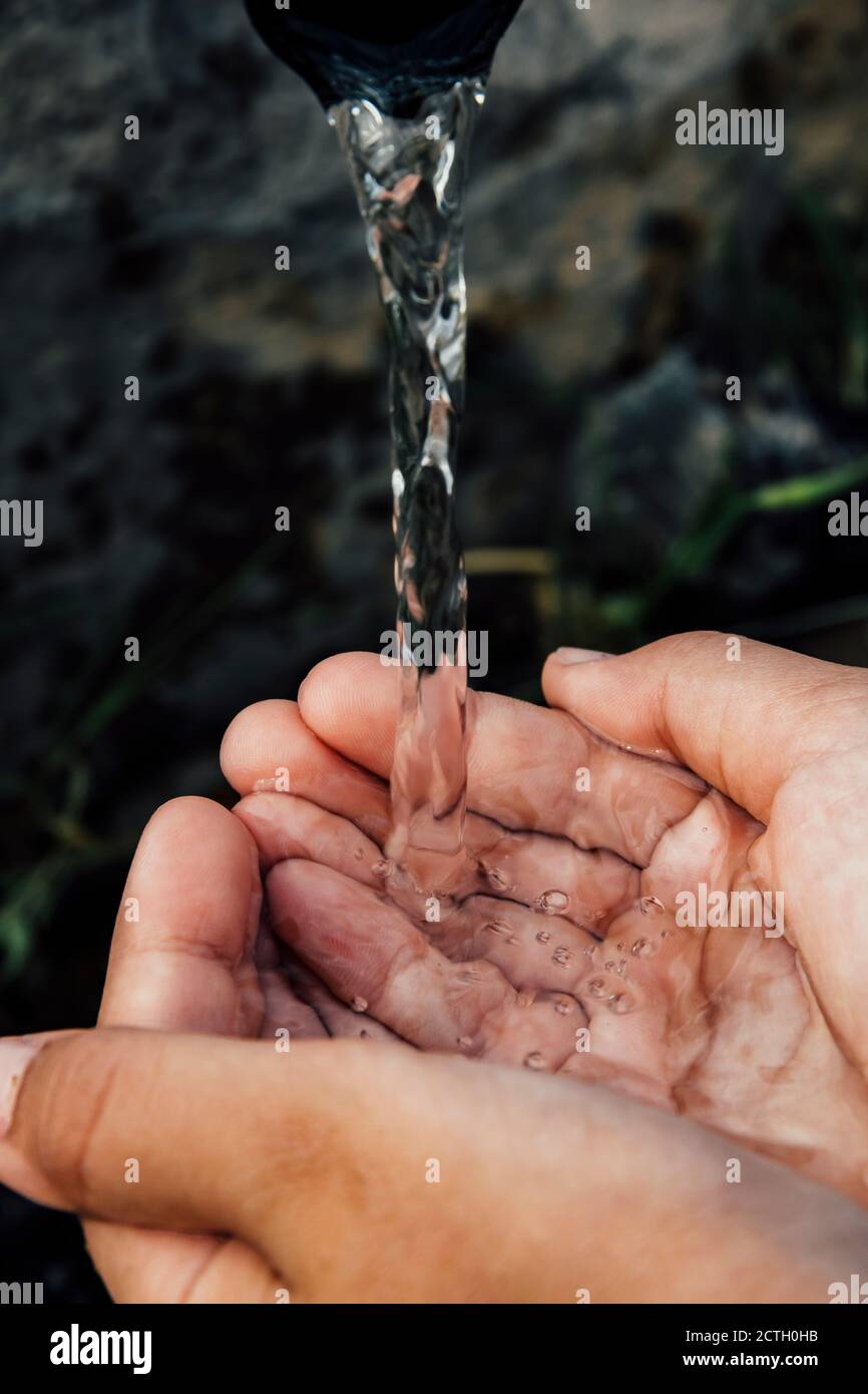 Two cupped hands holding cold fresh water streaming from a fountain in Bulgaria Stock Photo