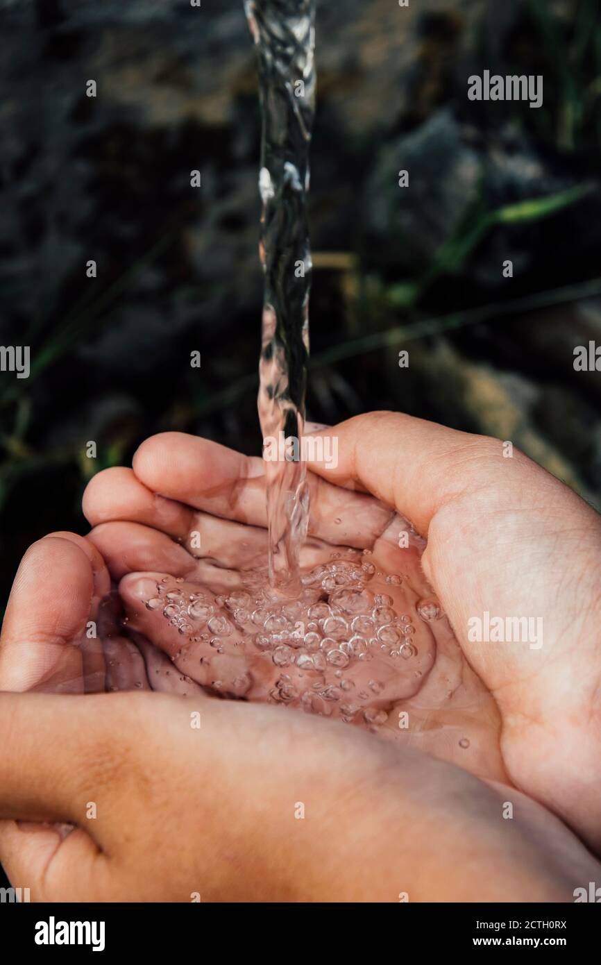 Two cupped hands holding cold freshwater streaming from a natural fountain in Bulgaria. Earth day photo, save the planet Stock Photo