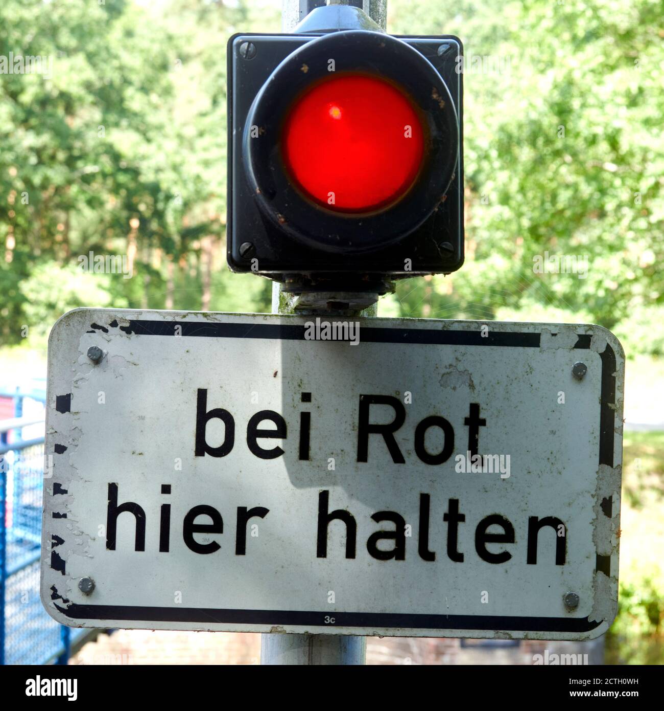 Red shining light above a sign with the German inscription: stop here at red! Stock Photo