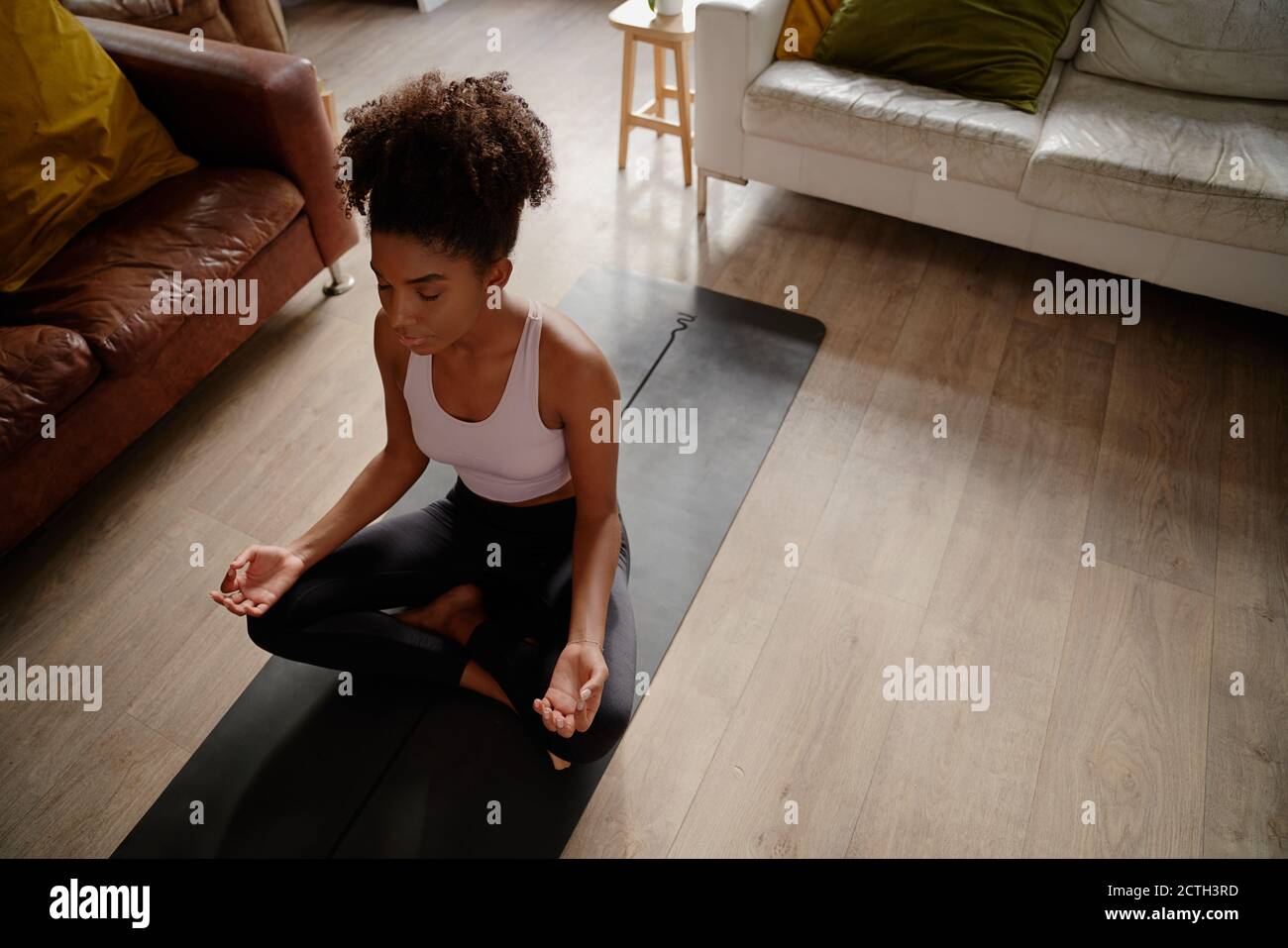 High angle view of african young woman in lotus position practising meditation and breathing exercise at home Stock Photo