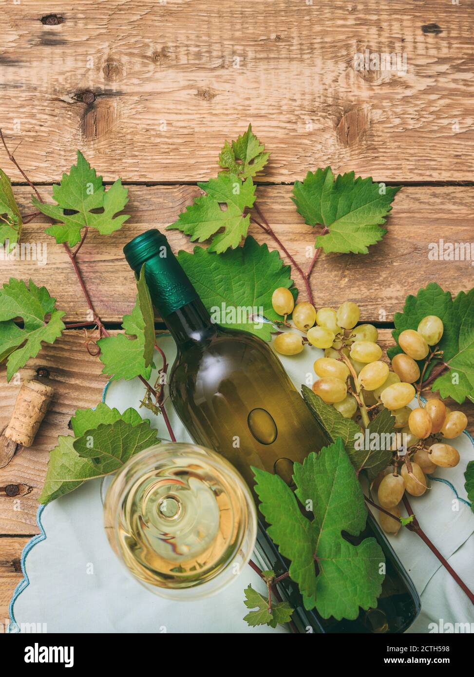 White wine glass and bottle and fresh grapes on wooden background, top view Stock Photo