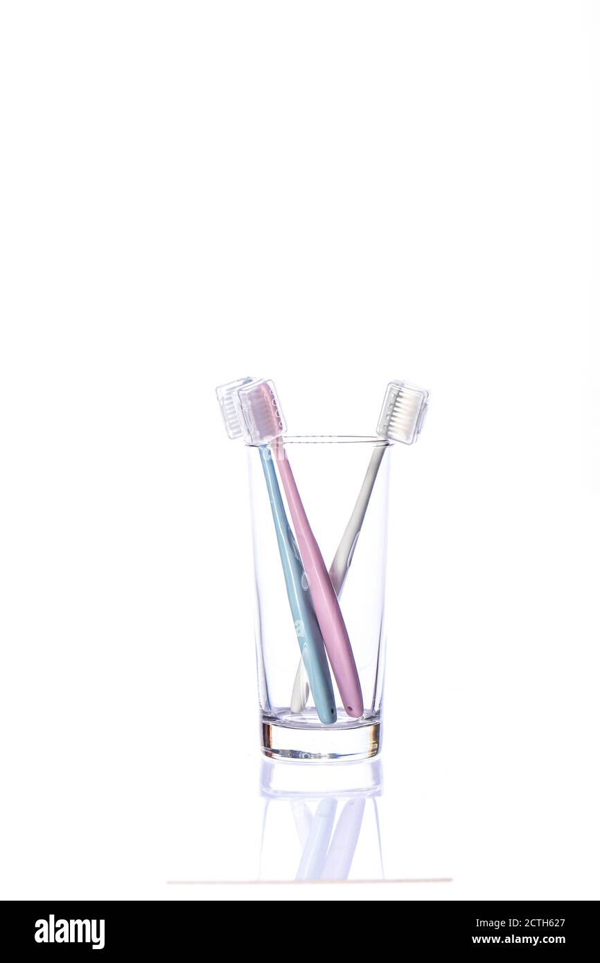 Three toothbrushes in transparent glass isolated on white background ...