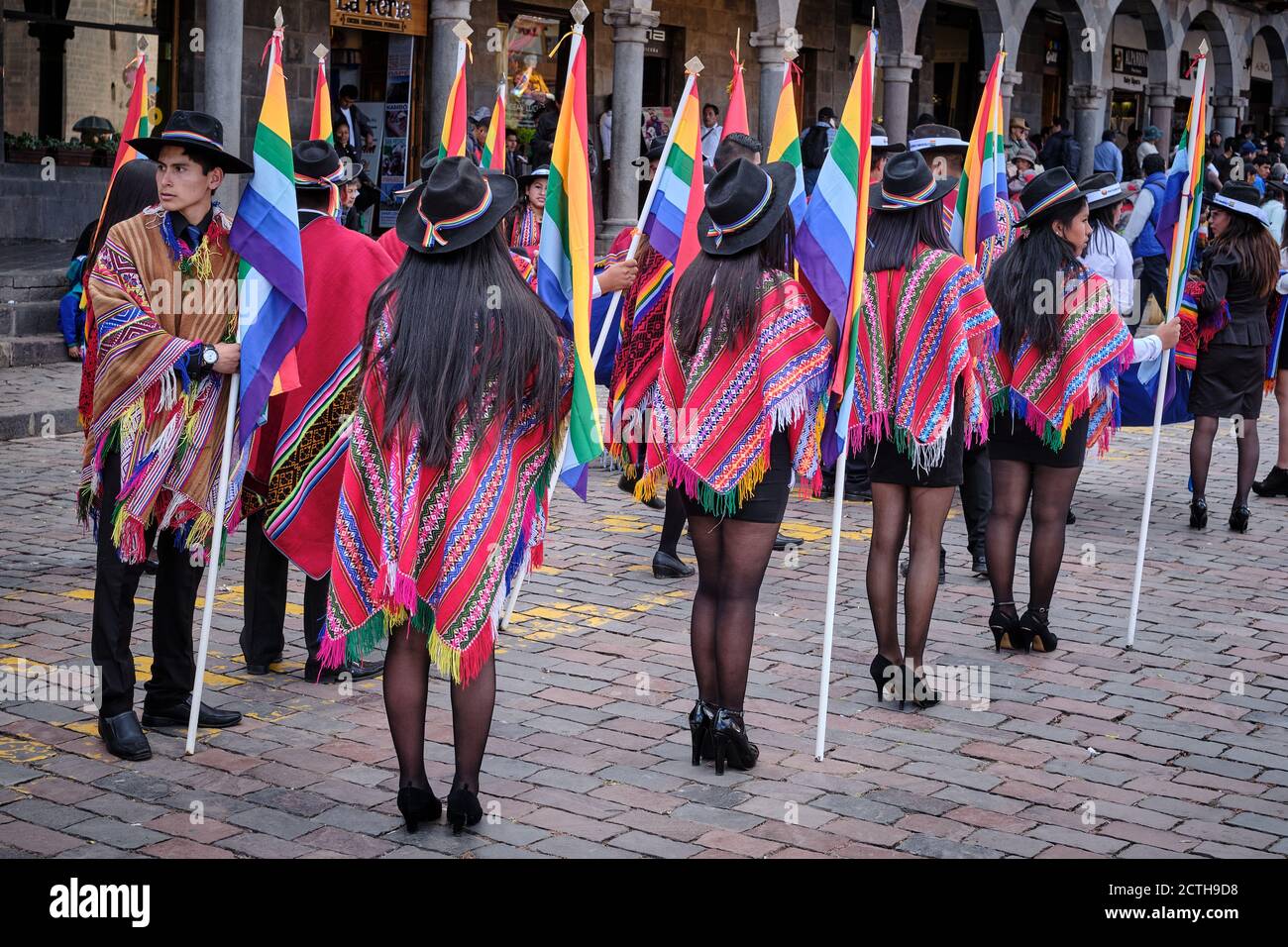 Female office workers women carrying the flag of Cusco rainbow flag, wait during the Inti Raymi'rata sun festival parade, Cusco, Peru Stock Photo