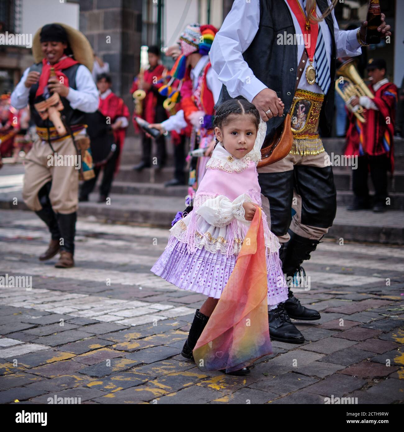 A young girl female child held by the hand by a man waits to join the parade in the Inti Raymi'rata sun festival over the winter solstice, Cusco, Stock Photo