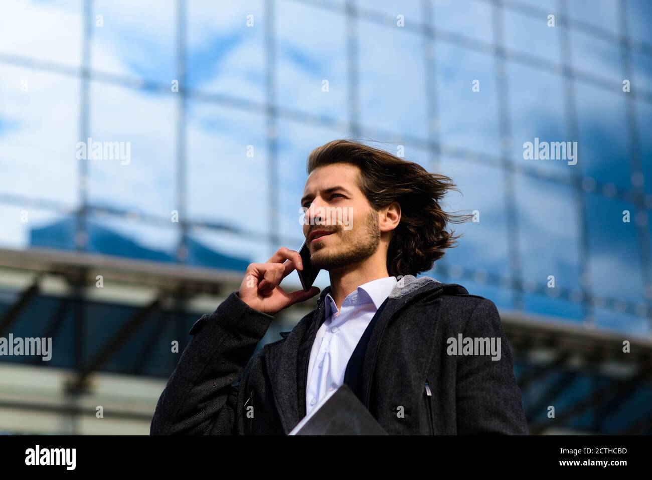 Portrait of an handsome businessman with phone, coffee cup in the city ...
