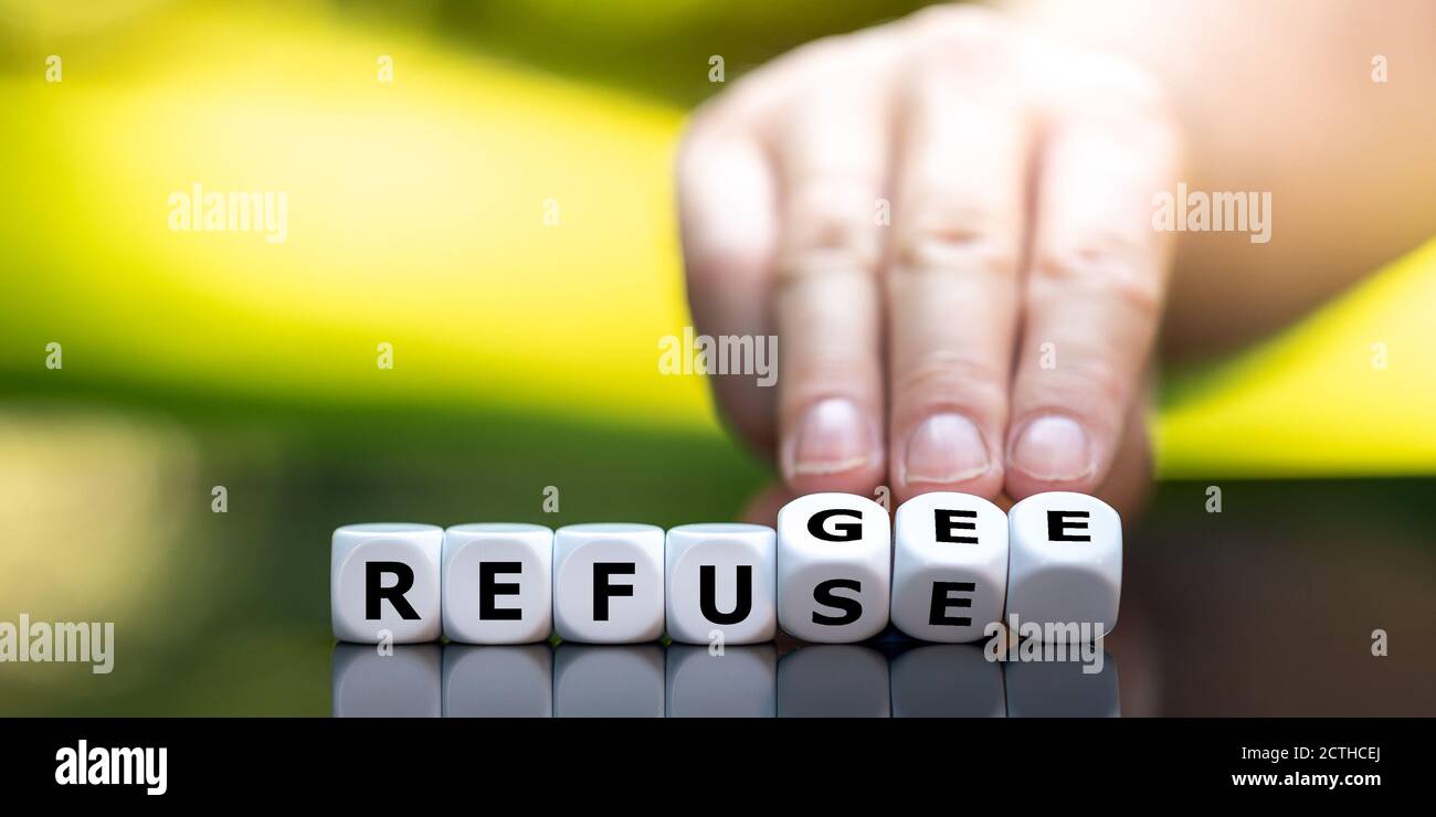 Hand turns dice and changes the word "refuse" to "refugee Stock Photo
