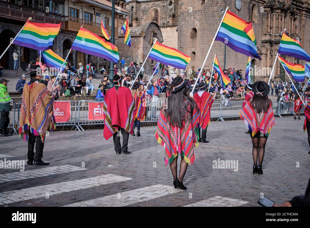 From behind, office workers carrying rainbow flags of Cusco in a parade during the Inti Raymi'rata sun festival over the winter solstice, Cusco, Peru Stock Photo