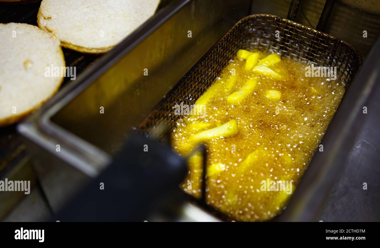 Frying French fries in deep fryer oven in hot boiling oil for dinner