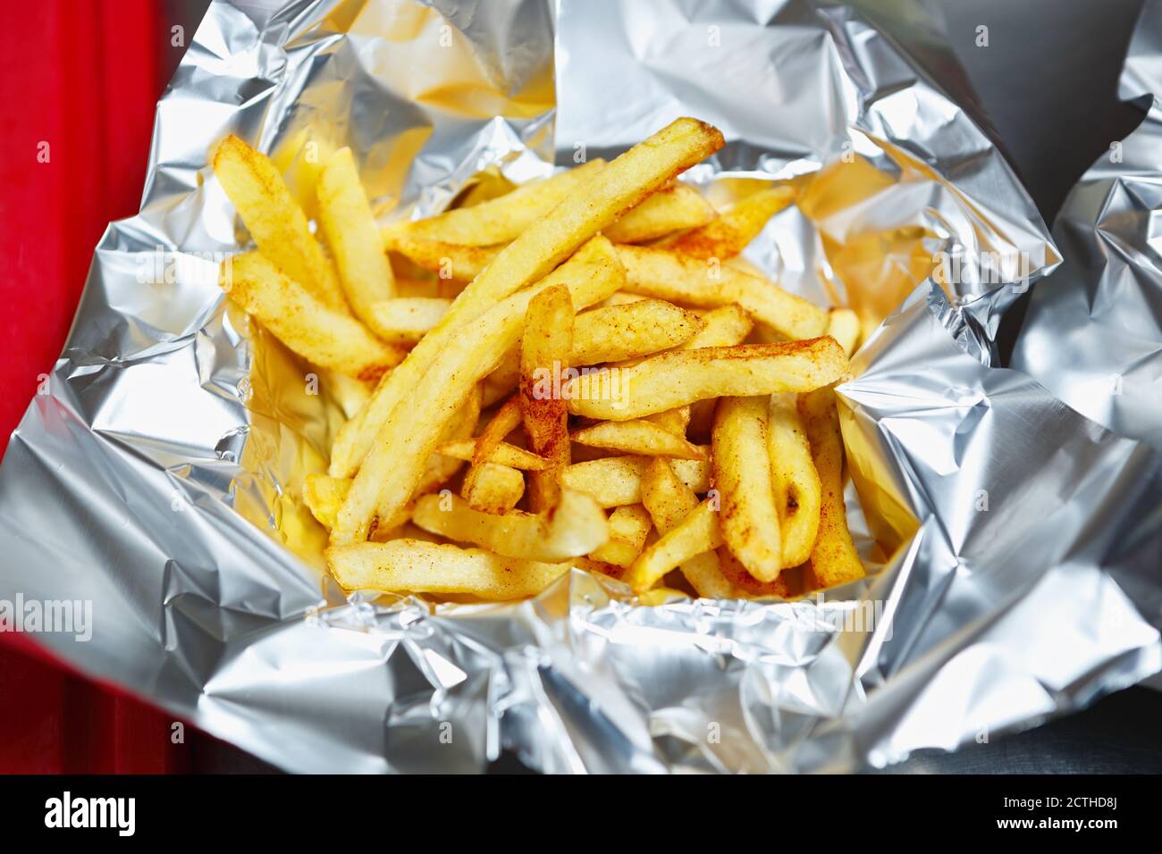 Delicious French fries served in tin foil for fast food delivery.Delicious golden potato chips