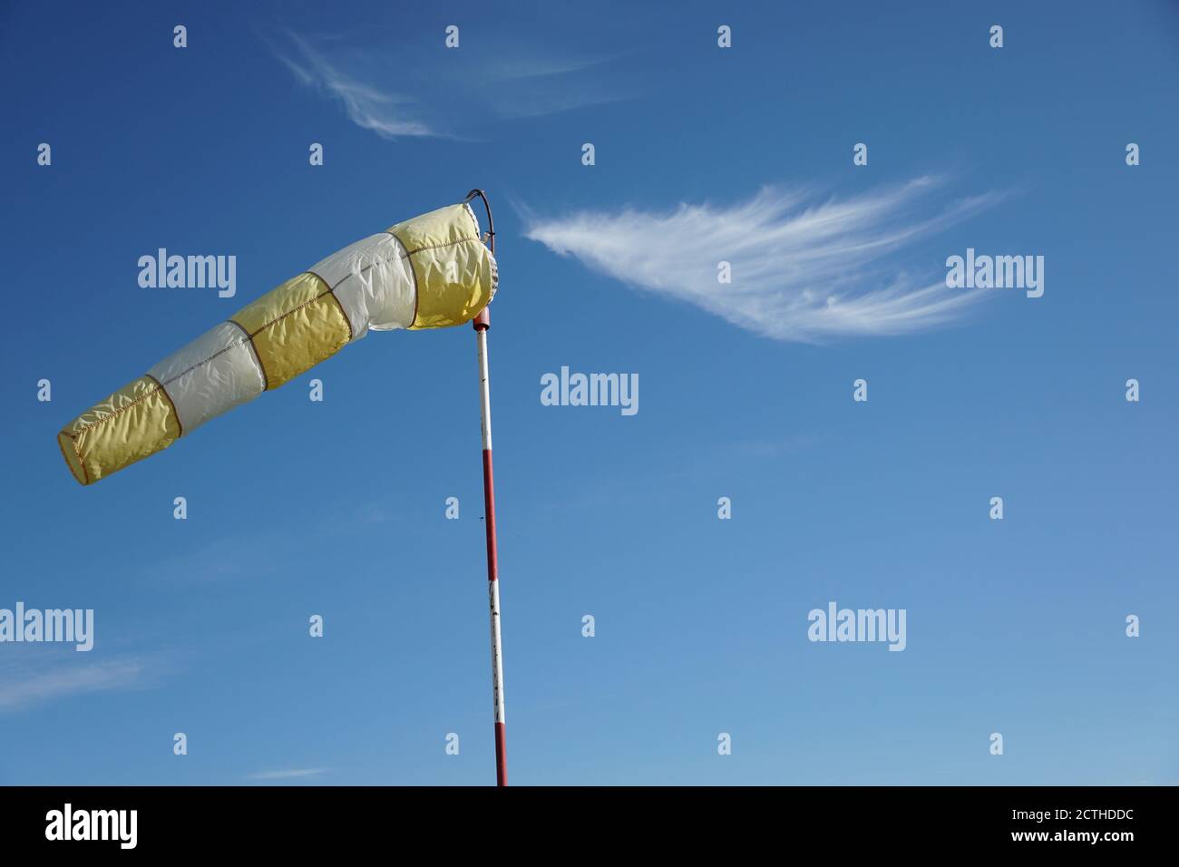 White - yellow wind sock on the pole on the blue sky background shot with copy space. Stock Photo