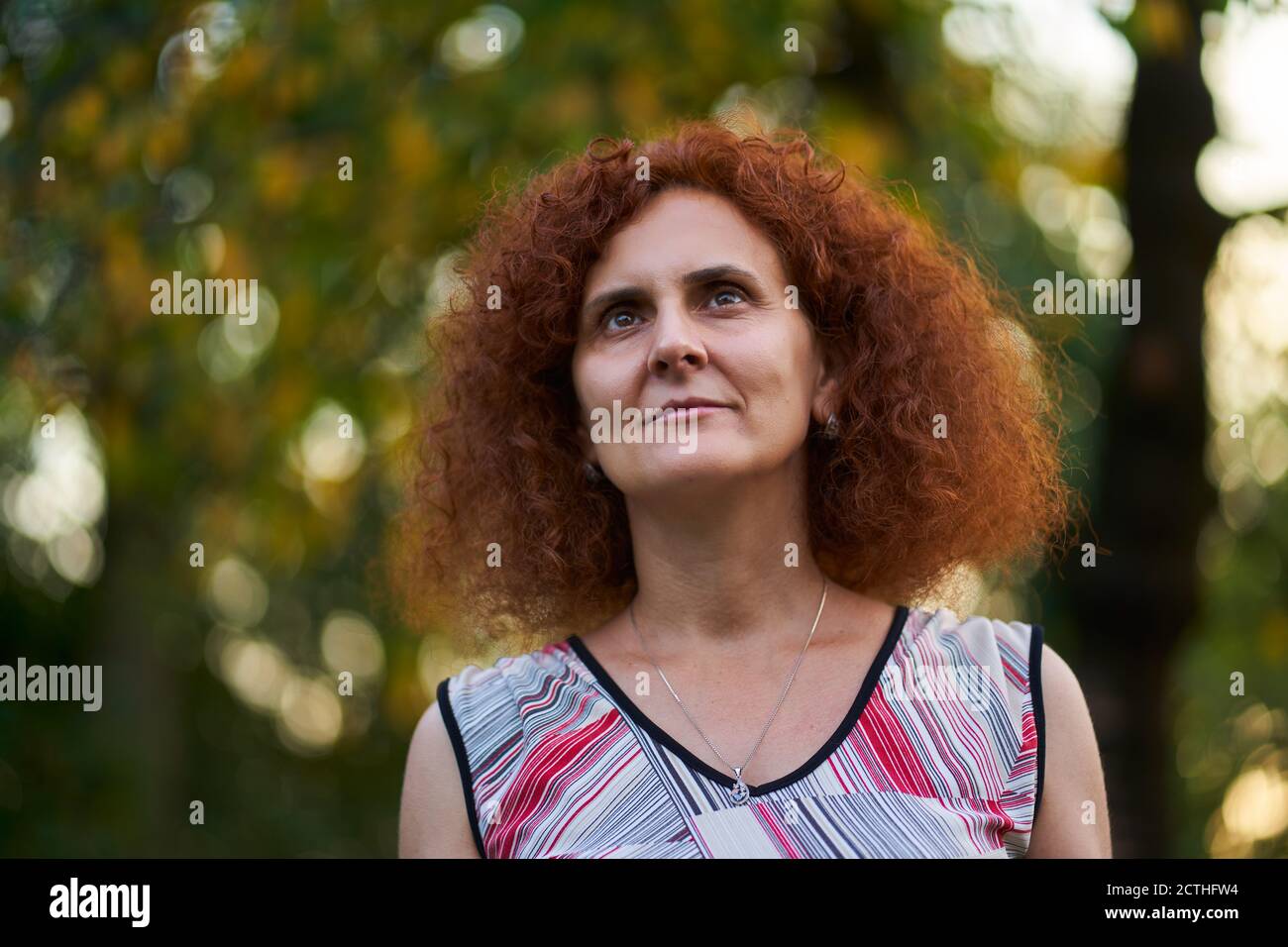 Curly redhead woman outdoor in the countryside, candid portrait Stock ...