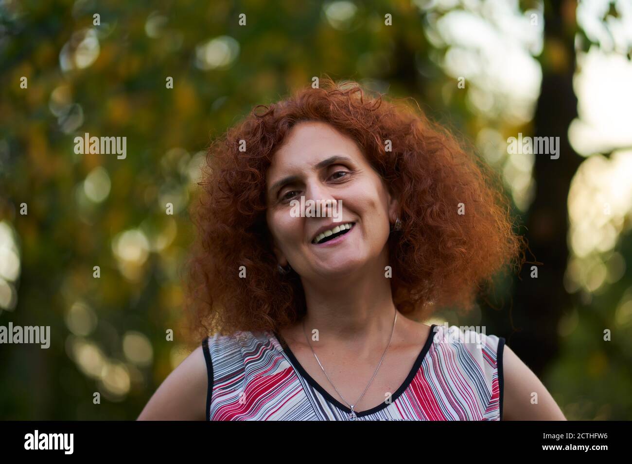 Curly redhead woman outdoor in the countryside, candid portrait Stock ...