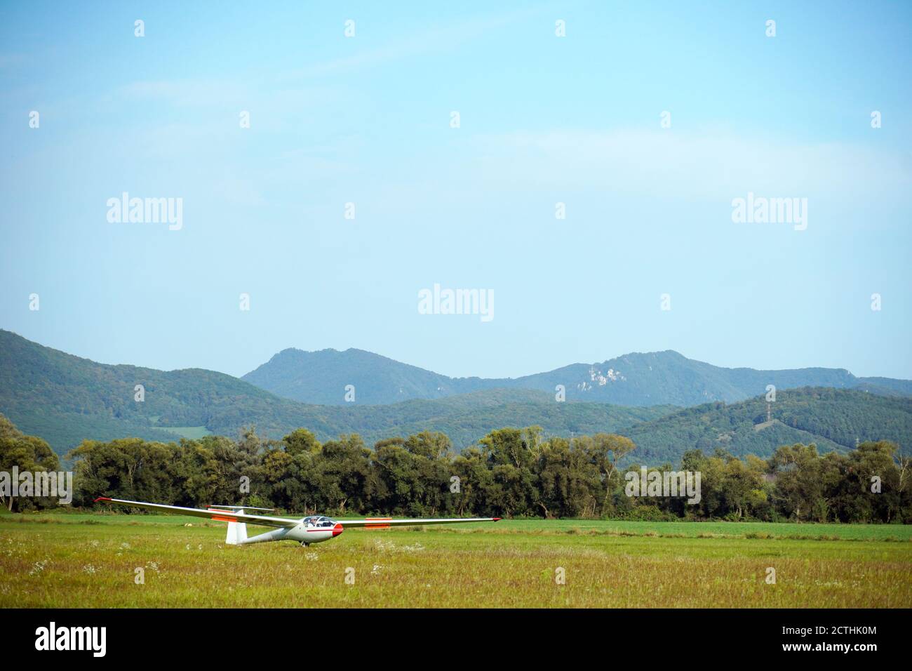 A glider or sailplane - aircraft landed on the grass, meadow, ground colourful photography. Stock Photo