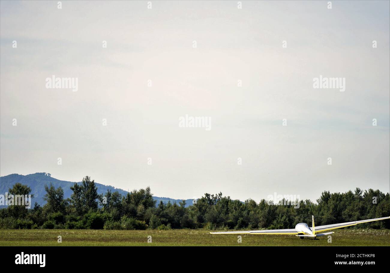 A glider or sailplane - aircraft landed on the grass, meadow, ground colourful photography. Stock Photo