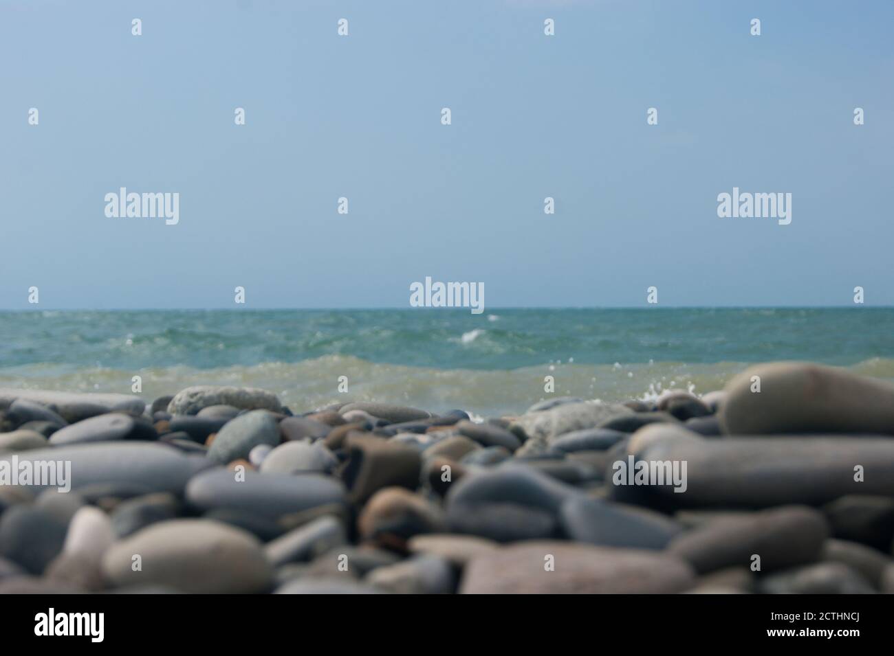 Beach. View of the sea and smooth horizon from the pebble beach. In the foreground are large pebble stones. It's a focus. Background for blog or site, photowallpaper for computer. Stock Photo