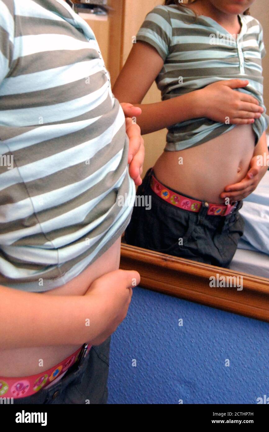 Girl looking at her tummy in a mirror Stock Photo
