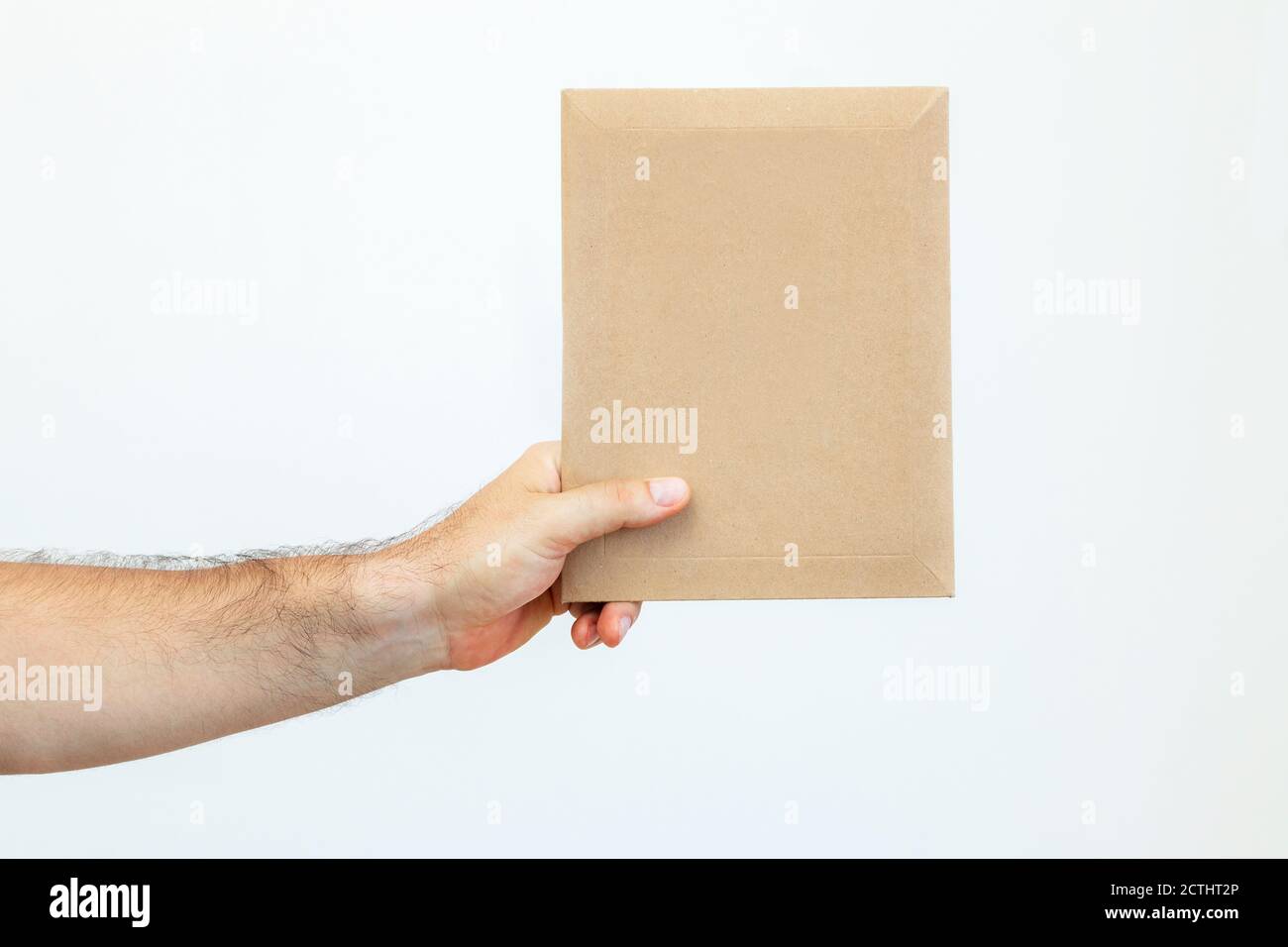 Man's hand holds a paper envelope. Delivery of documents by courier service. Express fast delivery. Postal parcel, package  Stock Photo