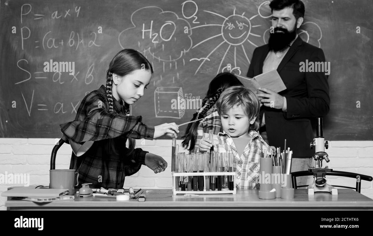 doing experiments with liquids in chemistry lab. chemistry lab. happy children teacher. back to school. kids in lab coat learning chemistry in school laboratory. Confident doctors team. Stock Photo