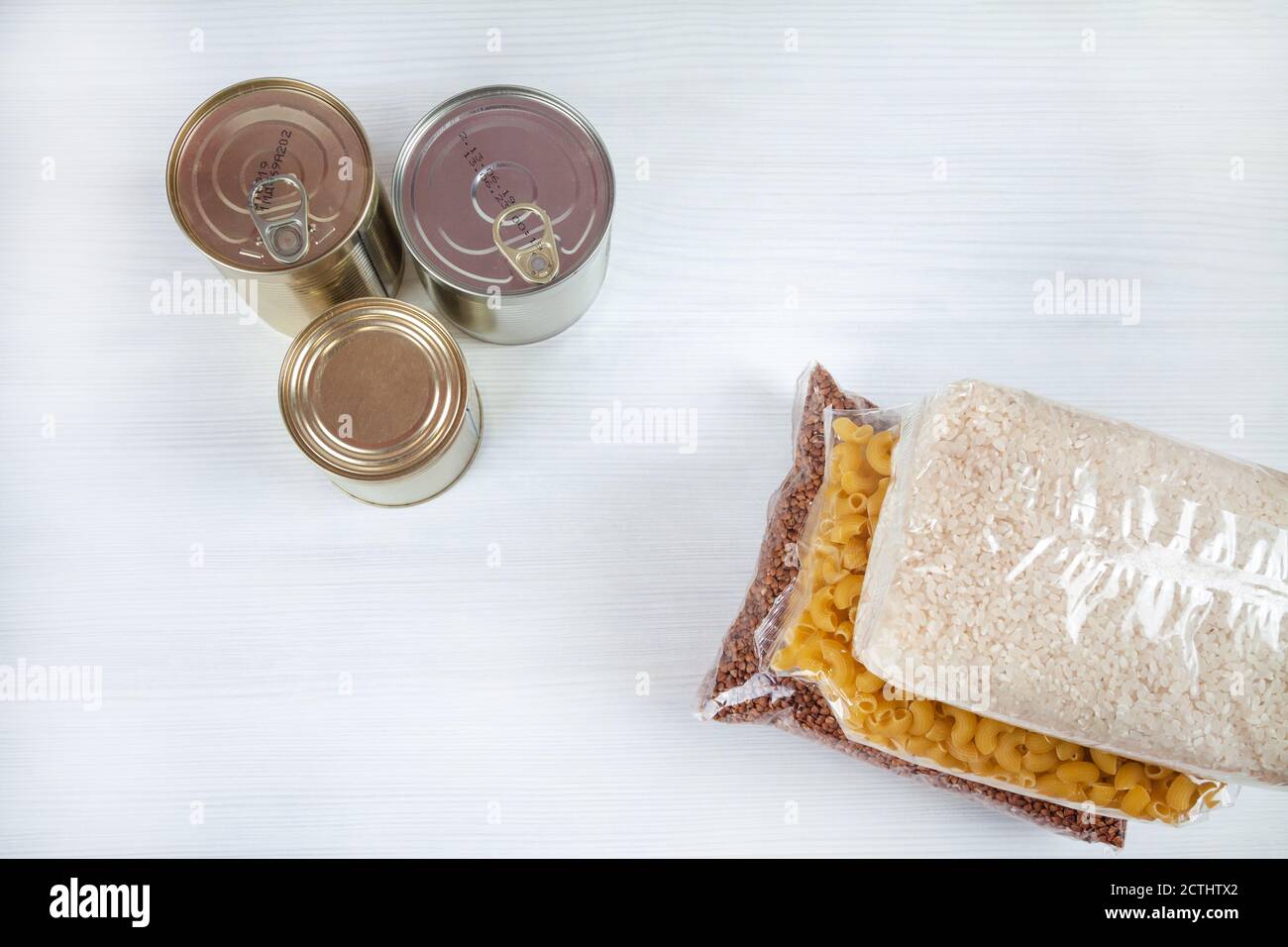 humanitarian assistance for poor and large families. Donation during crisis. Tin cans, canned food, stew, buckwheat, rice, pasta in transparent bags Stock Photo