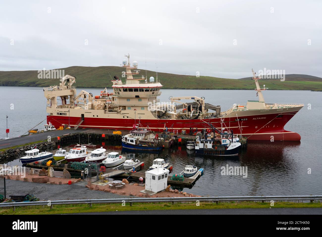 View of small harbour and pier with fishing vessels at Housetter, North Roe, Shetland, Scotland, UK Stock Photo