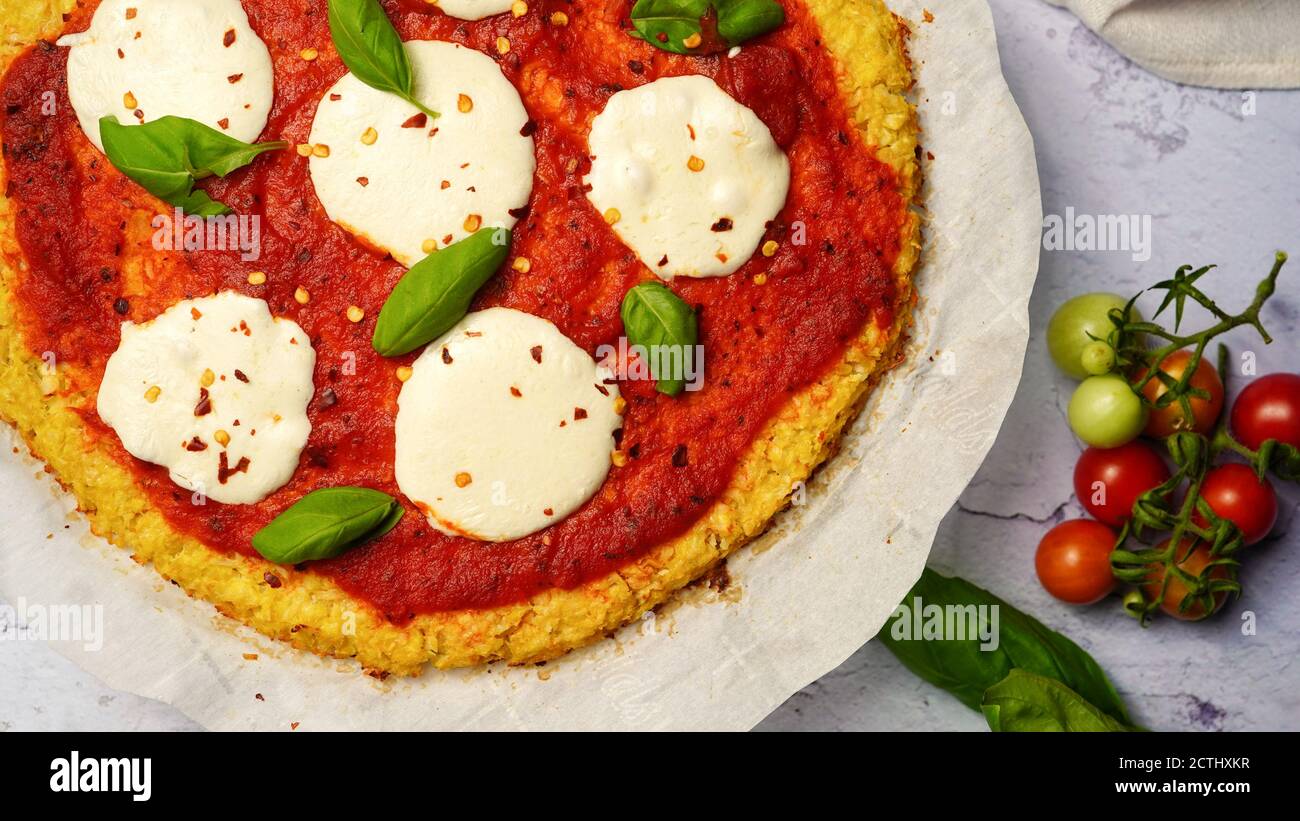 Homemade Cauliflower Crust pizza topped with fresh basil leaves Stock Photo