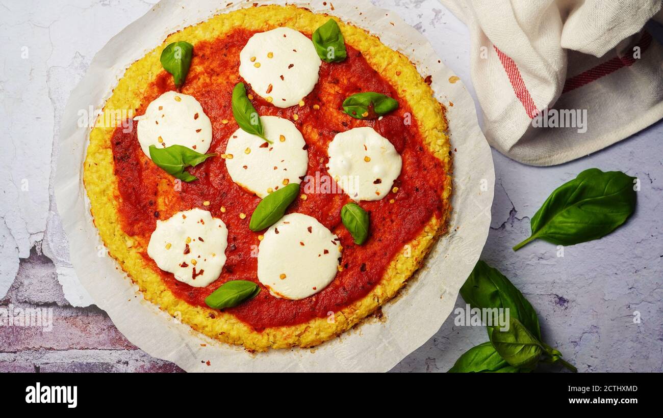 Homemade Cauliflower Crust pizza topped with fresh basil leaves Stock Photo