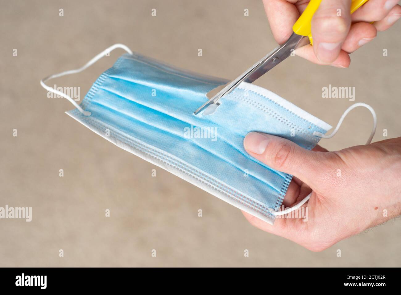 Blue disposable face mask, covering or PPE being cut in half. This symbolises a growing public opinion against a second lockdown in the UK Stock Photo