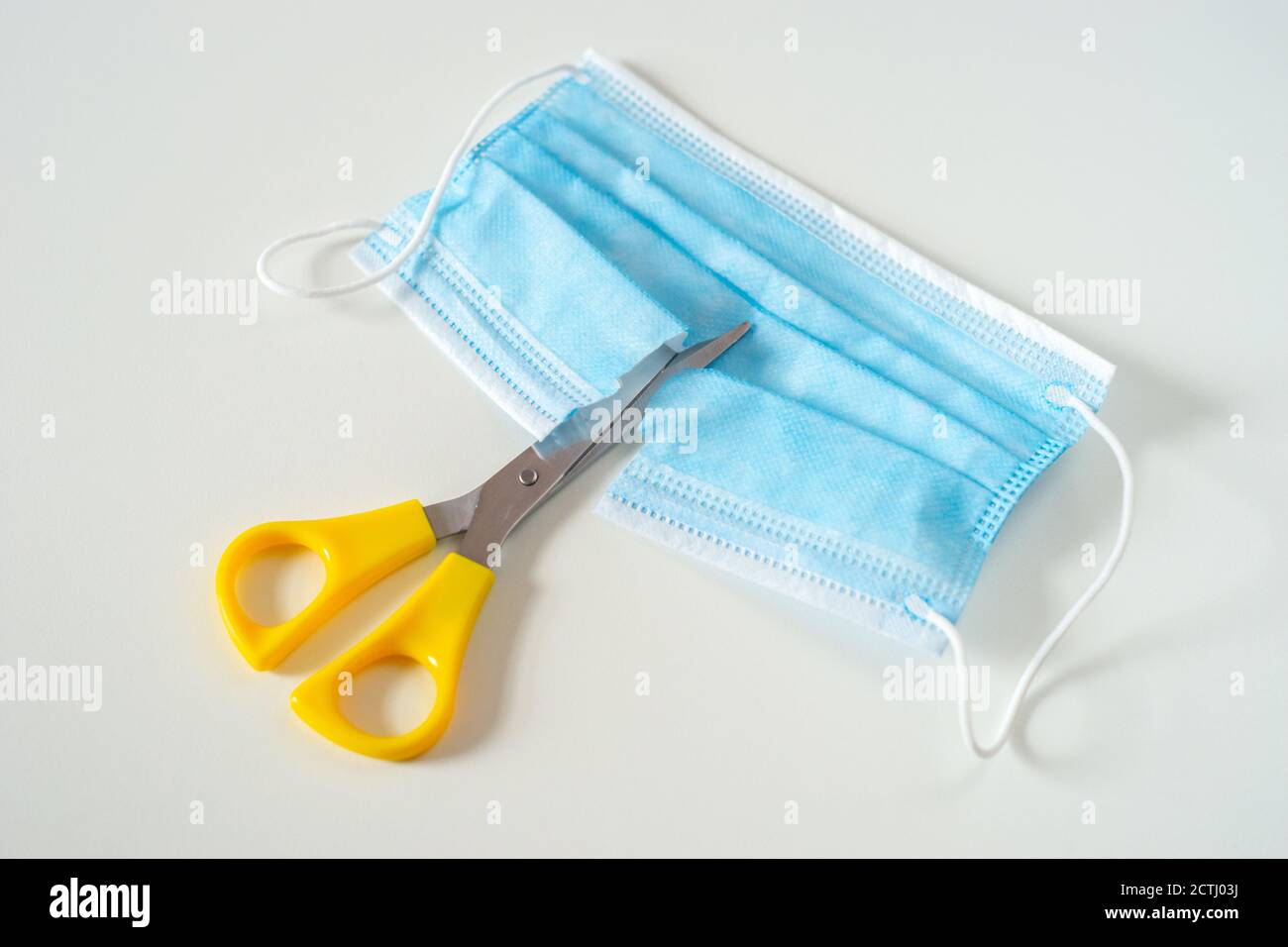 Blue disposable face mask, covering or PPE cut in half. This symbolises a growing public opinion against a second lockdown in the UK Stock Photo