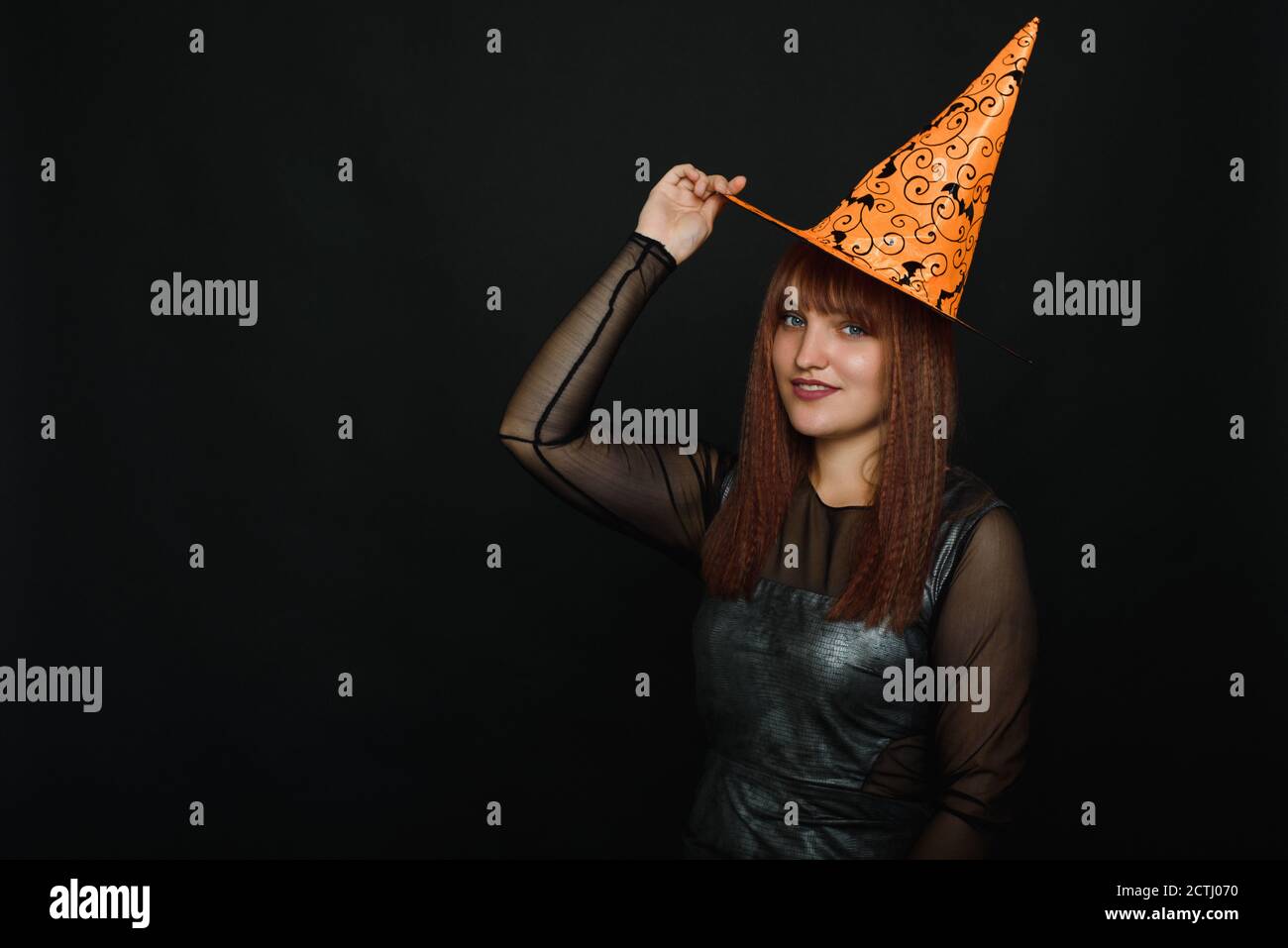 Portrait of winsome, blonde lady look at camera on black background. Photo of cute woman wearing conical hat. Stock Photo