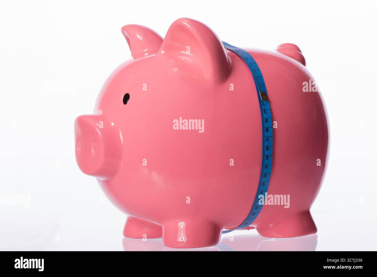 pink piggy bank tied with blue measuring tape at waist isolated on white Stock Photo