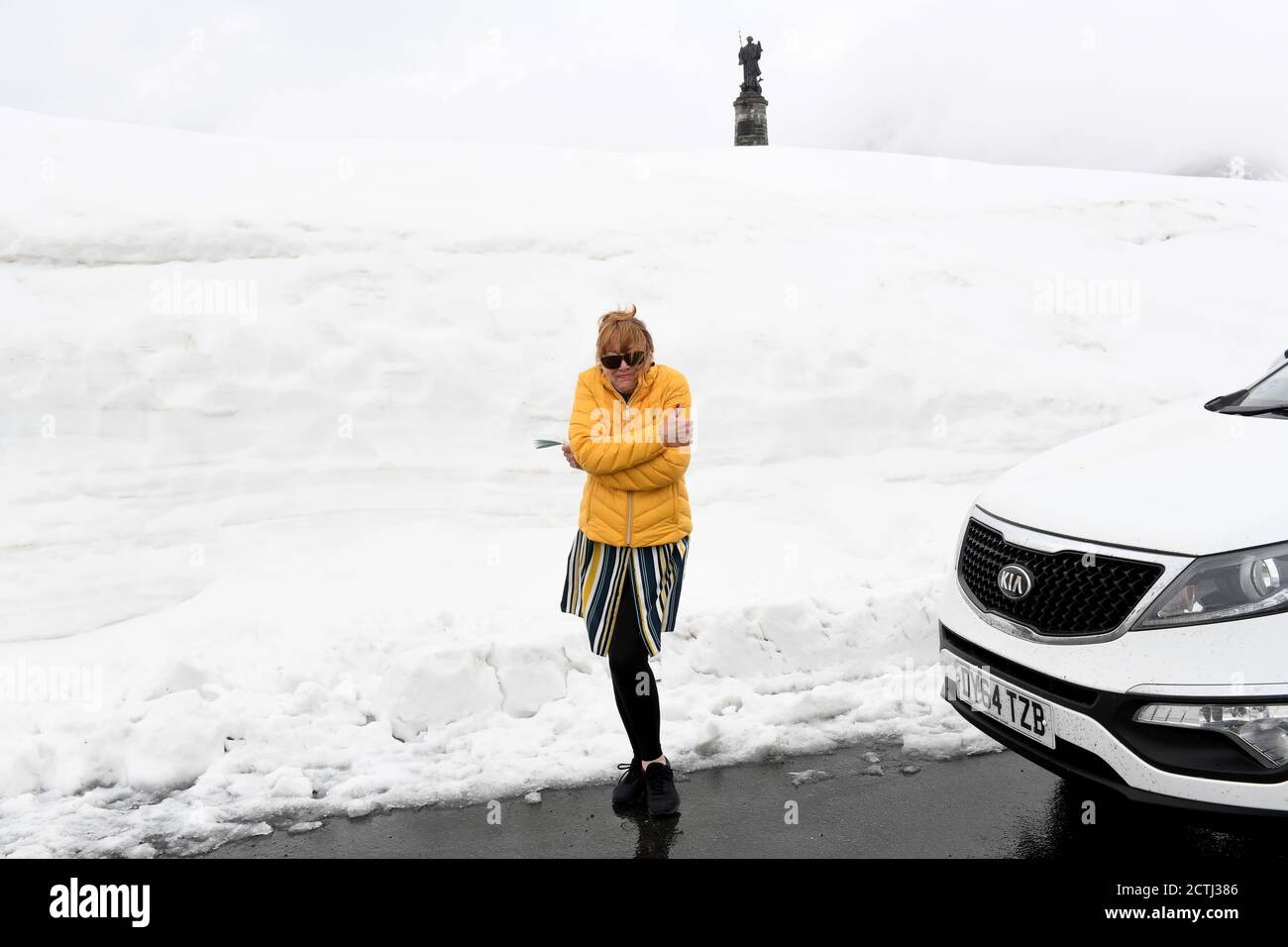 Woman tourist feeling the cold in the summer of 2019 at abandoned border customs post on Great St Bernard Pass on the Italian - Swiss border Stock Photo
