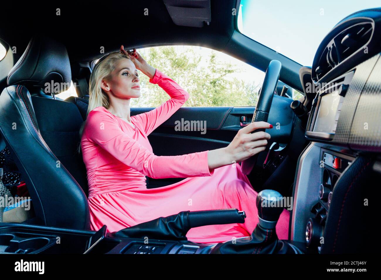 Beautiful fashionable woman blonde driver behind the wheel of a car