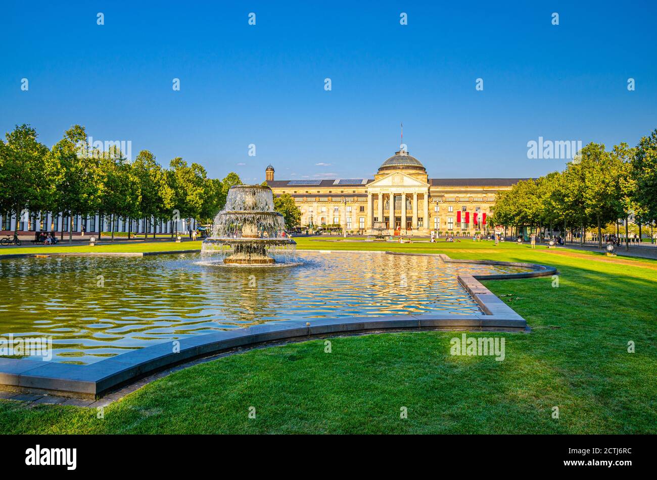 Wiesbaden, Germany, August 24, 2019: Kurhaus or cure house spa and casino building and Bowling Green park with grass lawn, trees alley and pond with fountain in historical city centre, State of Hesse Stock Photo