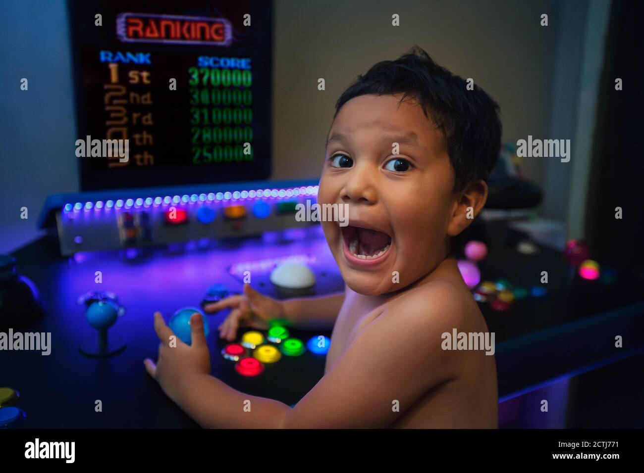 First place ranking or high score by a young gamer with an enthusiastic expression while gaming on a home arcade. Stock Photo