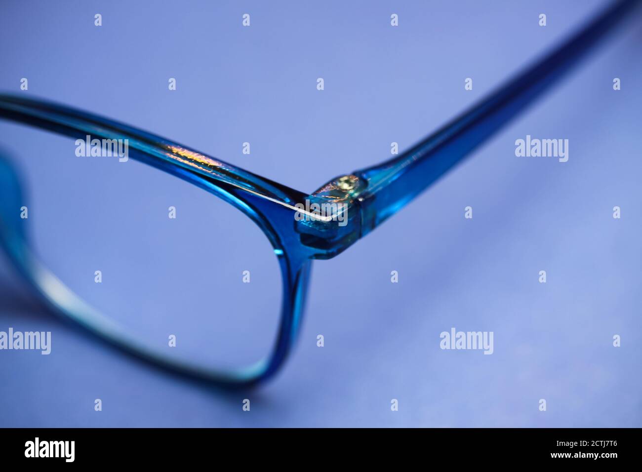 Closeup of isolated blue eyeglass lens with earpiece hinge on blank background Stock Photo