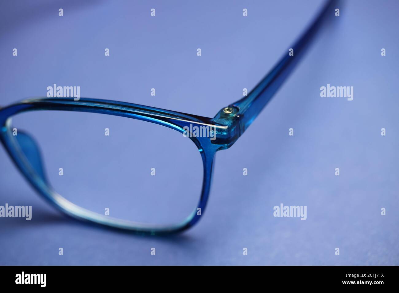 Closeup of isolated blue eyeglass lens with earpiece hinge on blank background Stock Photo