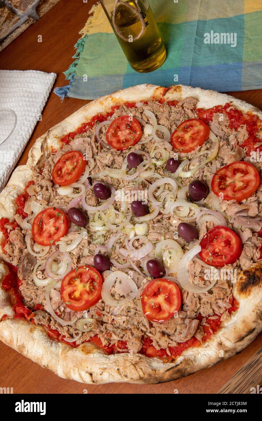 Pizza tuna fish, onion, tomato and black olive on wooden table. Traditional Brazilian Pizza. Stock Photo