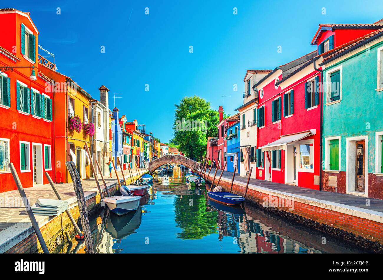 Colorful houses of Burano island. Multicolored buildings on fondamenta embankment of narrow water canal with fishing boats and stone bridge, Venice Province, Veneto Region, Italy. Burano postcard Stock Photo
