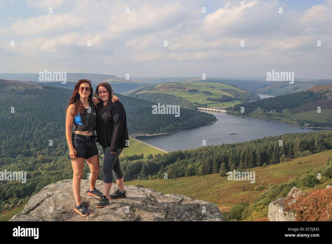 Two walkers stand on the edge of Bamford Edge overlooking Ladydower Reservoir on a day of uncertainty as the government consider putting the UK back into lockdown due to a spike in Covid 19 cases. Stock Photo