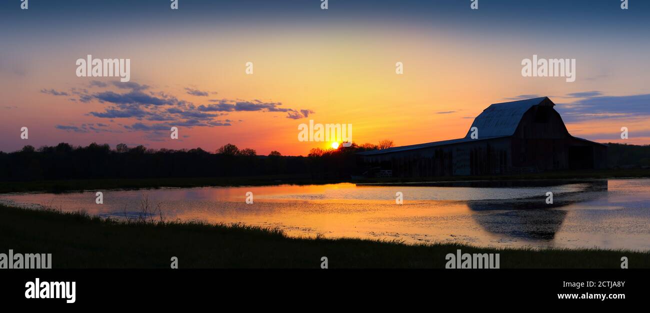 Old Barn and Sunset Reflected in Water Stock Photo