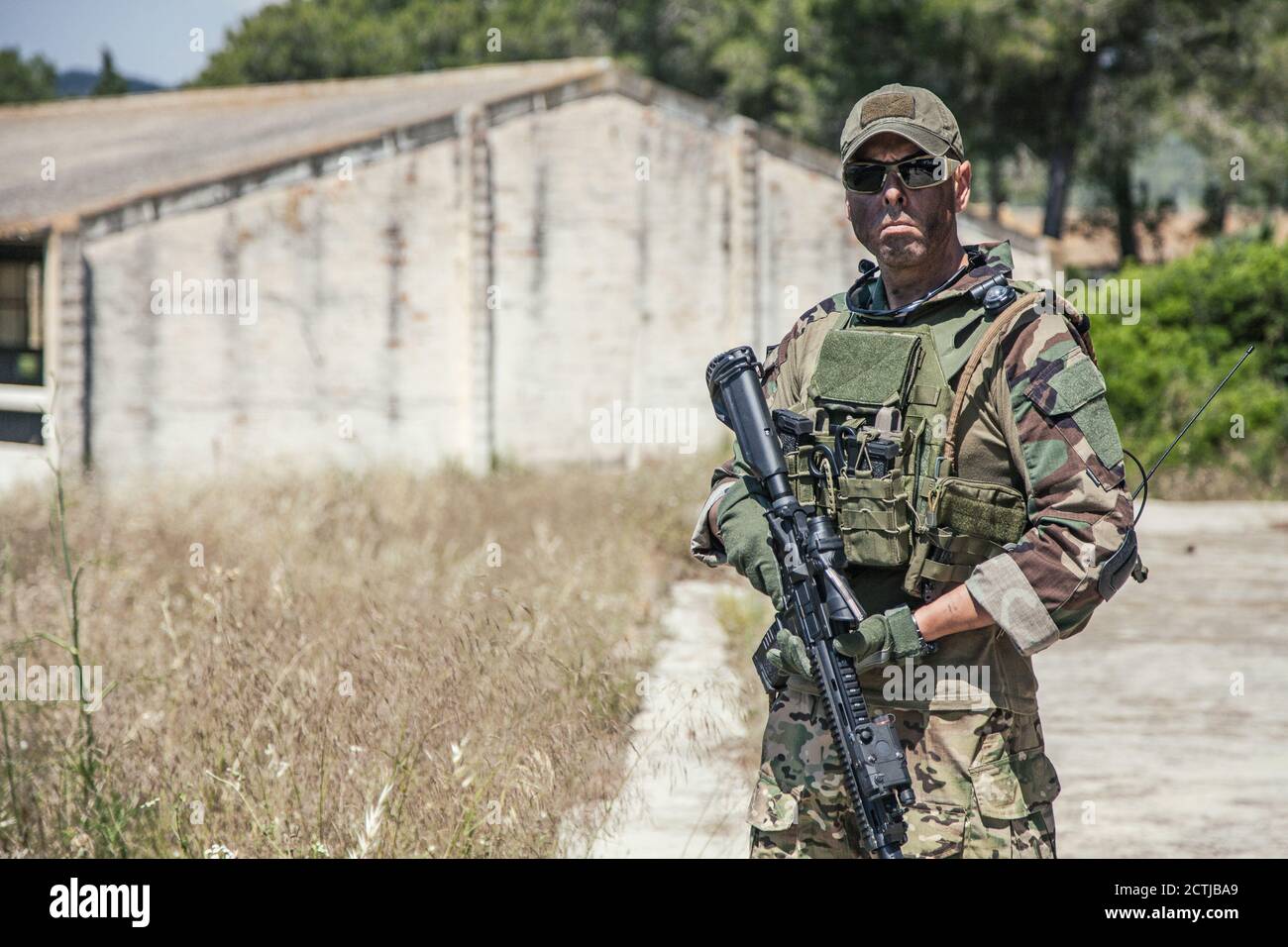 Navy SEALs fighter in ballistic goggles, equipped military ammunition and  body armour, holding service rifle, looking in camera while standing  outdoors. Special forces soldier half-length portrait Stock Photo